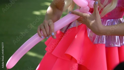 An animator girl makes a figurine from a balloon at her birthday party.