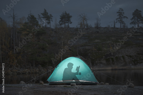 A man spends leisure time in a tent reading a book. Take a break from the crazy world