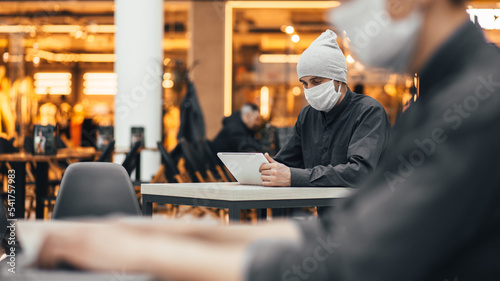 food court visitors wearing protective masks using their laptops