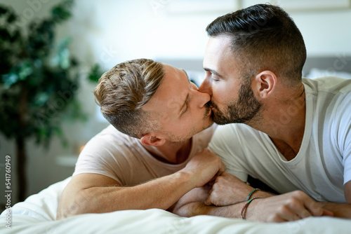 Two men couple in bed on a beautiful white bedroom