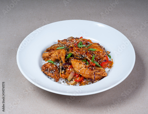Asian cuisine. Close-up of white plate of rice and herb spicy fried chicken.