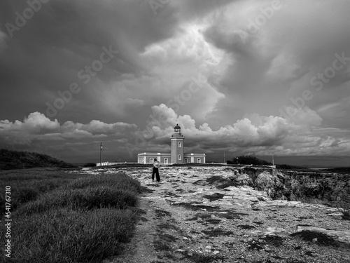 Grayscale view of a human walking toward the Faro Los Morrillos under the cloudy sky photo