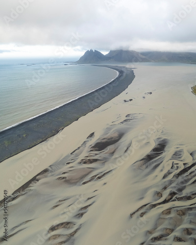 Aerial view of water formation at river estuary and Fjorur beach with mountain in background, Iceland. photo