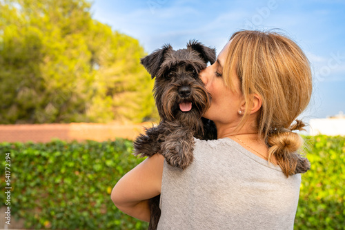 Beautiful woman hugging and kissing dog. Dog and owner together outdoors. Love and friendship between dog and owner photo