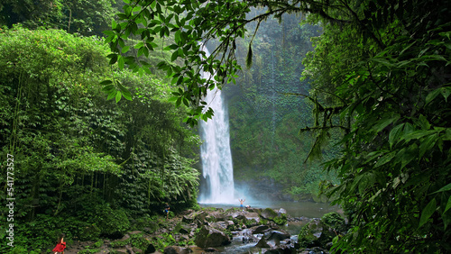 waterfall with rocks among tropical jungle with green plants and trees and water falling down