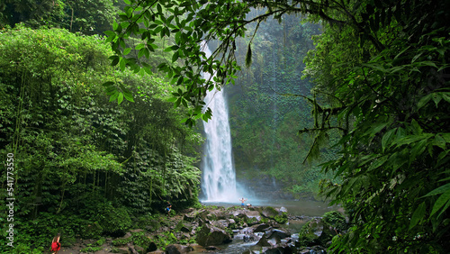 waterfall with rocks among tropical jungle with green plants and trees and water falling down