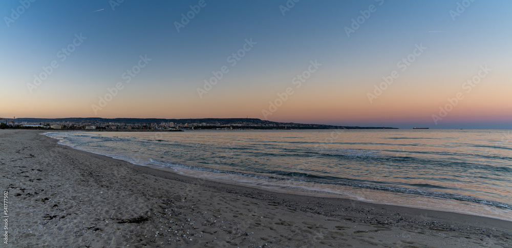 panorama landscape of Asparuhovo Beach at sunset and the Bulgarian Black Sea city of Varna in the background