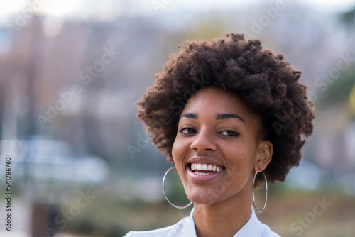 Afro girl smiling in a park with her hair in the air