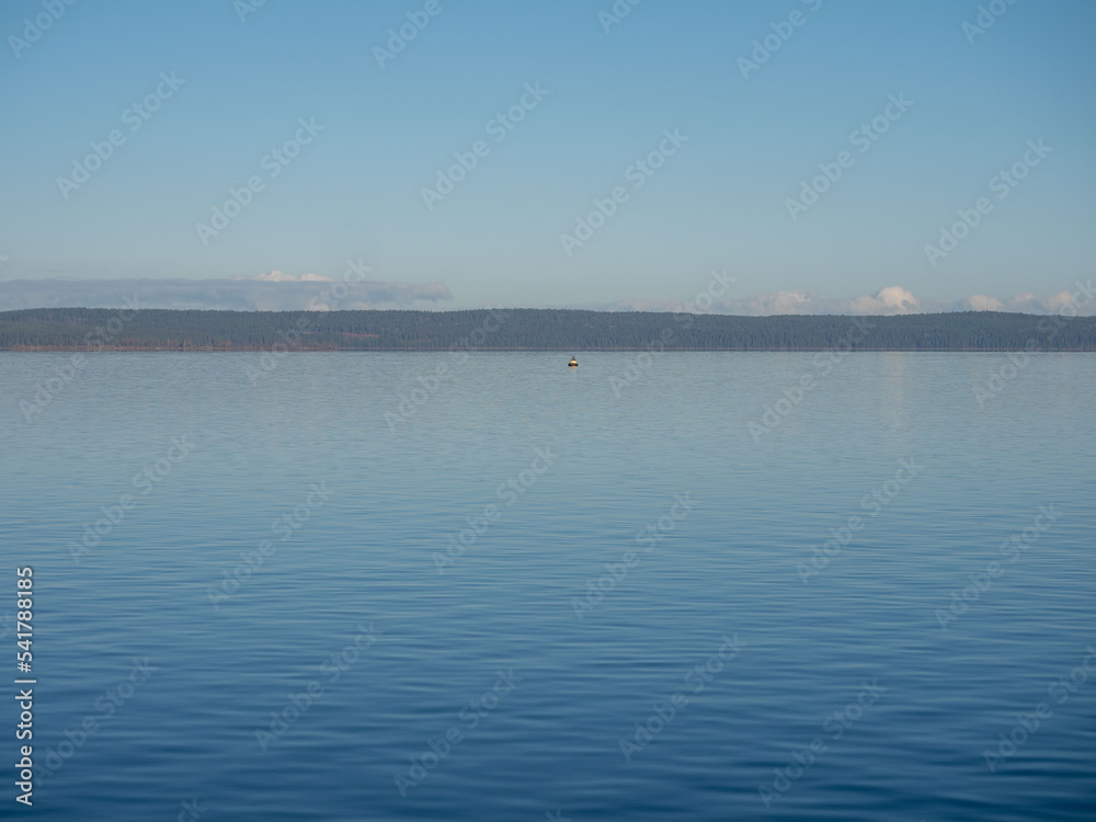 Calm blue water of Onega Lake in Karelia in northwestern Russia on a clear, windless, sunny autumn day