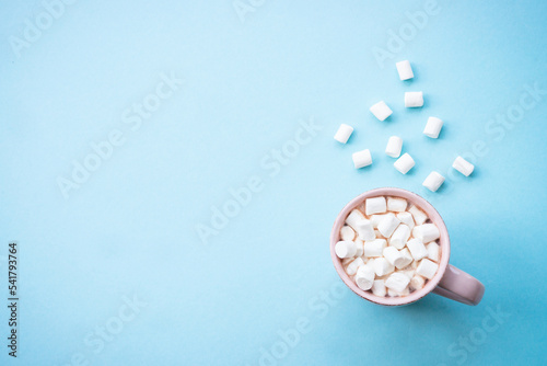 Hot chocolate with marshmallows on blue. Cozy winter concept, flat lay image.