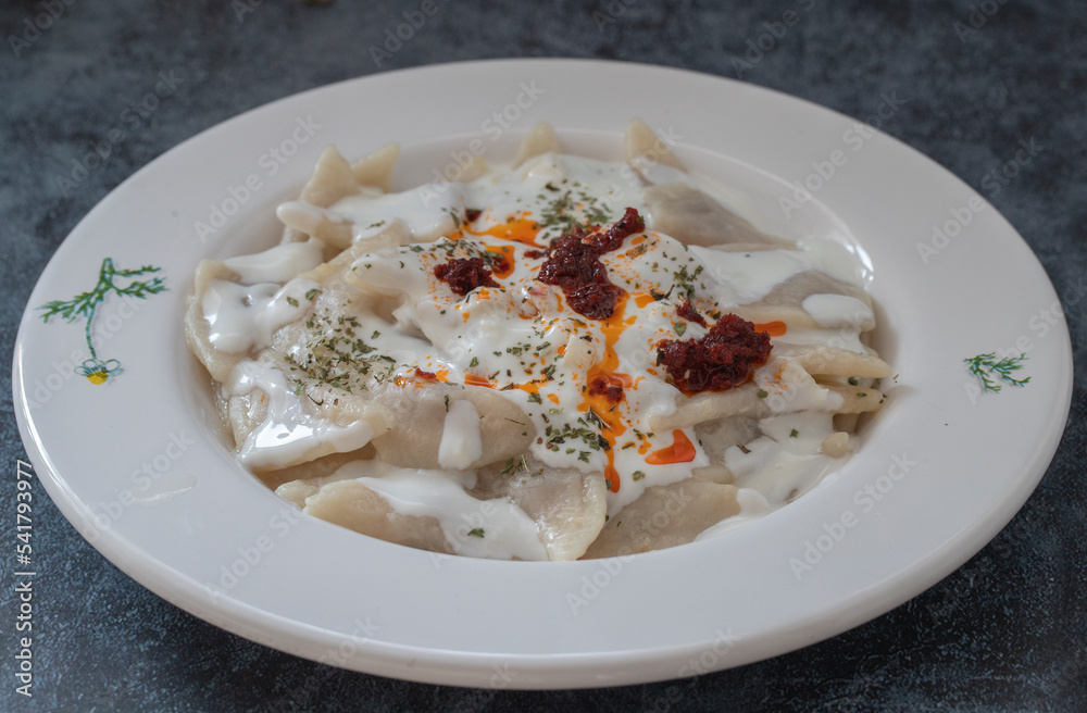 Turkish traditional food ravioli with yoghurt and tomato sauce in plate, manti Turkish traditional food ravioli with yoghurt and tomato sauce in plate, manti