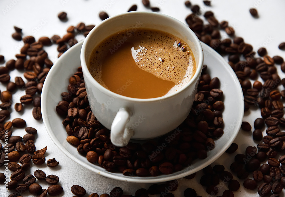 White porcelain cup with coffee and coffee beans on a white background. Tea pair with foamy coffee and coffee beans.