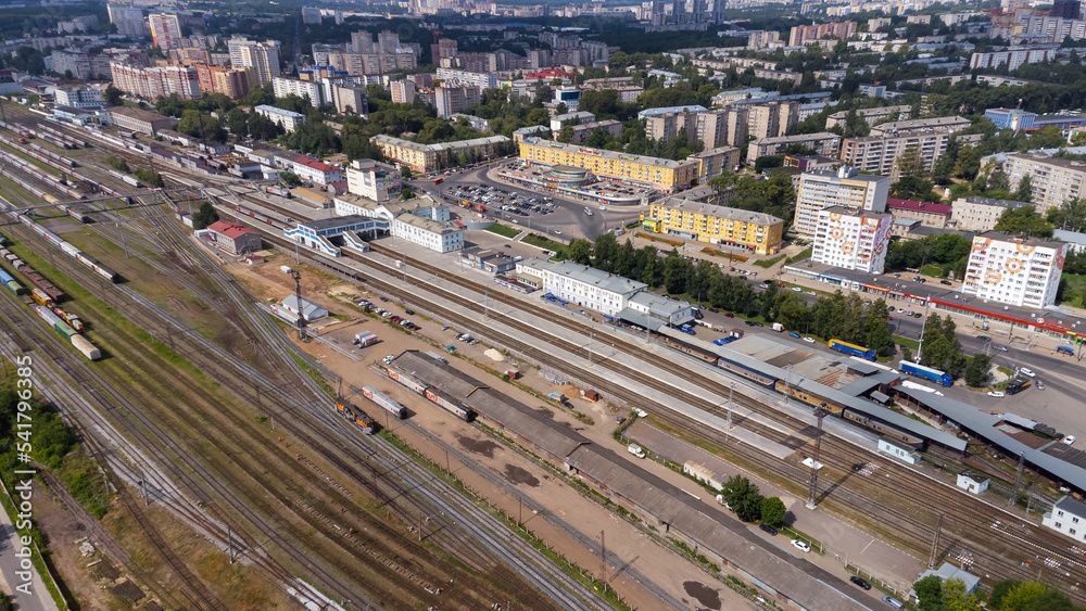 City, locality. Railway station. Passenger and cargo transportation. Residential area on a sunny summer day. Apartment buildings, high-rise buildings. The view from the drone, from above.