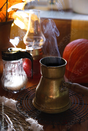 Fototapeta Naklejka Na Ścianę i Meble -  Yellow metal vintage cerve with steam over it with pumpkin and autumn leaves on wooden table, cozy autumn morning concept.