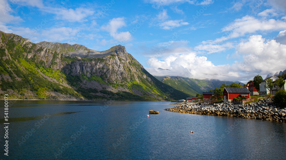 panorama of the landscape of the senja island, northern norway, small colourful houses on the seashore under huge rocks and cliffs, paradise beaches in rocky fjords