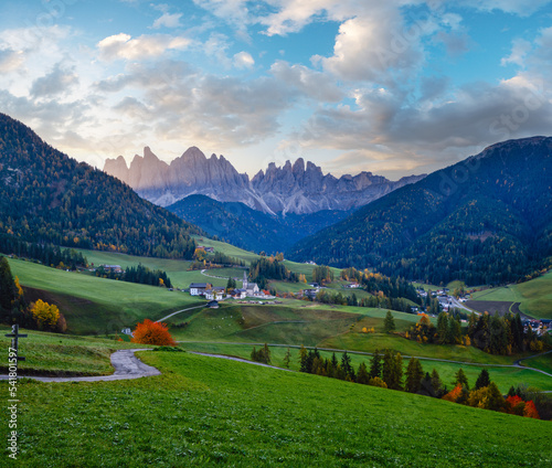 Autumn daybreak Santa Magdalena famous Italy Dolomites village view in front of the Geisler or Odle Dolomites mountain rocks. Picturesque traveling and countryside beauty concept background.