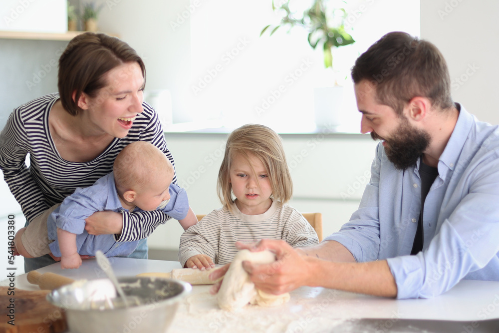 Young parents playing with children in the kitchen Young parents playing with children in the kitchen