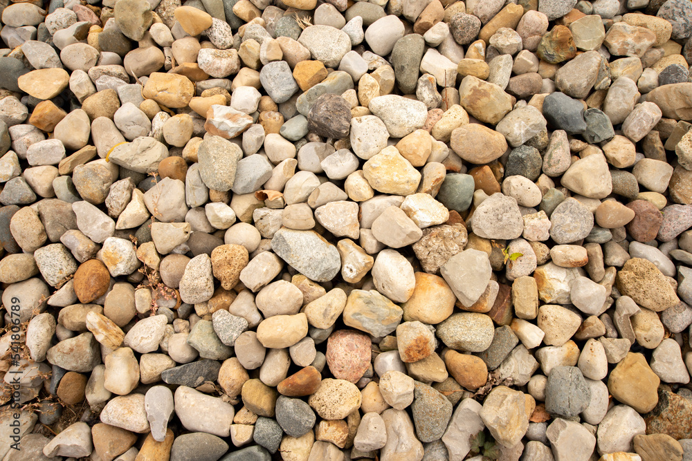Stones of various sizes in gray, white, yellow, orange and light purple. Some are smooth and round. Others are jagged and irregular. Stones of various sizes in gray, white, yellow, orange and light purple. Some are smooth and round. Others are jagged and irregular.