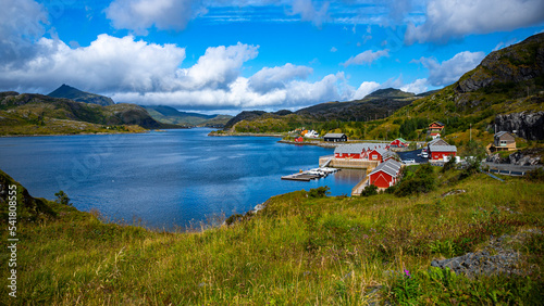 the harsh landscape of the norwegian fjords on the Lofoten islands, small houses by the sea with huge mountains above them