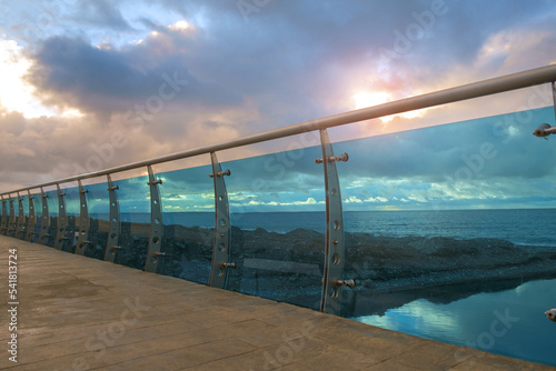 Fototapeta Naklejka Na Ścianę i Meble -  Modern bridge construction detail made by steel and glass on the beach with cloudy sky background
