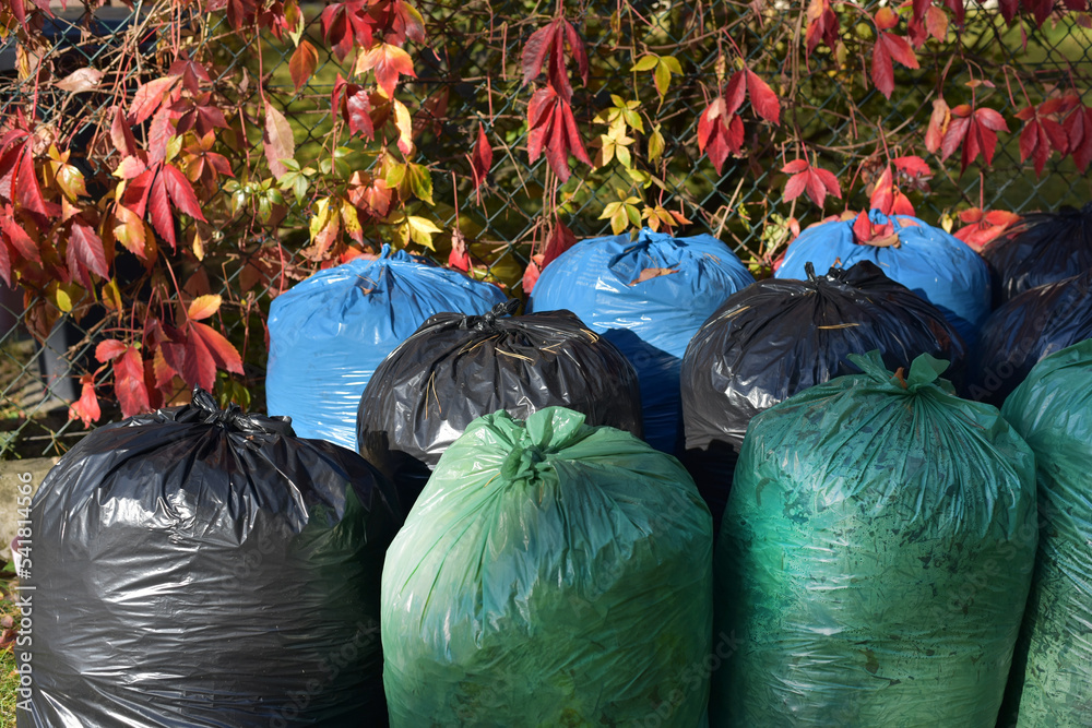 Multicolored trash bags under the fence StockFoto Adobe Stock