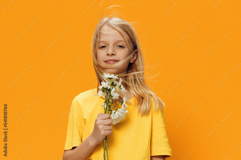 a beautiful cute girl of school age stands with a bouquet of daisies in ...