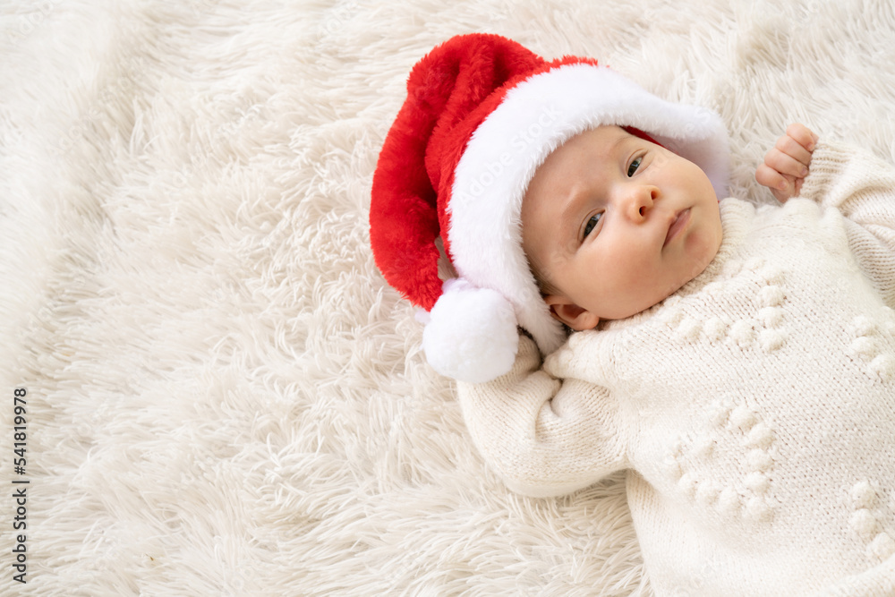Christmas portrait of cute little newborn baby girl, wearing santa hat and hugging little cute snowman toy, winter time