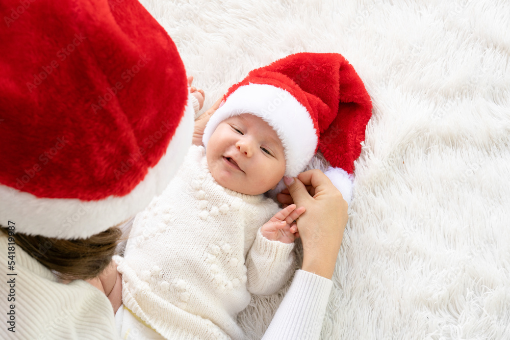portrait of cute little newborn baby girl with her mother wearing santa hat winter time outdoors. portrait of cute little newborn baby girl with her mother wearing santa hat winter time outdoors.