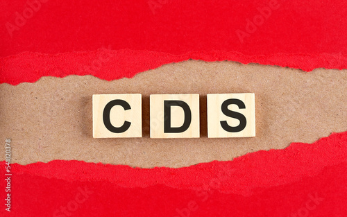 CDS CREDIT DEFAULT SWAP word on wooden cubes on red torn paper , financial concept background