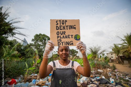 Young african girl holding a sign stop denying our planet is dying. Pollution concept