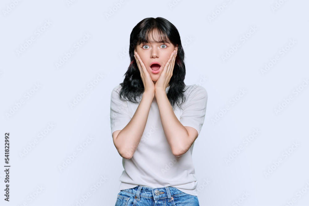 Young shocked woman looking at camera on white background Young shocked woman looking at camera on white background