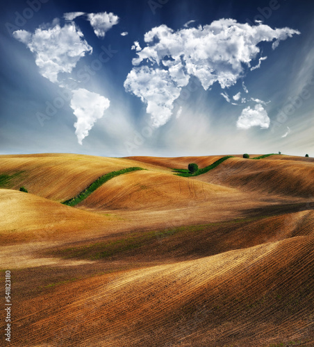 clouds in the form of a map of the world over the field. Travel and landscape concept. hilly field