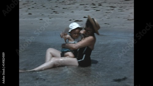 Sitting on the Shore 1960 - A mother sits on the shore and plays in the water with her young daughter in Miami, Florida, 1960.