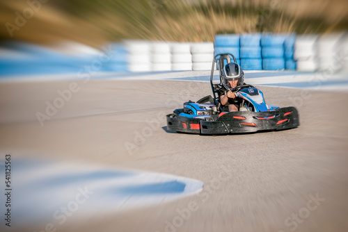 zooming effect of a teenager driving a kart at the exit of a curve of a karting circuit, face of speed and concentration while driving a go kart, out of focus