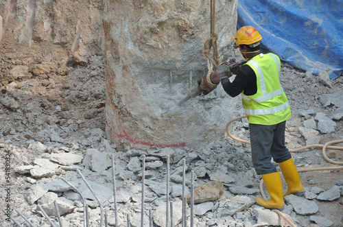 JOHOR, MALAYSIA -JANUARY 13, 2015: A construction workers cutting foundation pile using hacking method at the construction site. He using the heavy duty mobile hacker machine. 