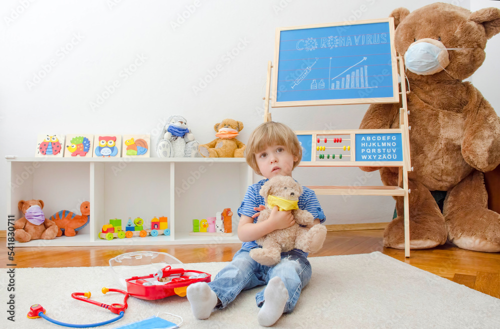 Cute child boy in home quarantine playing doctor with toys wearing