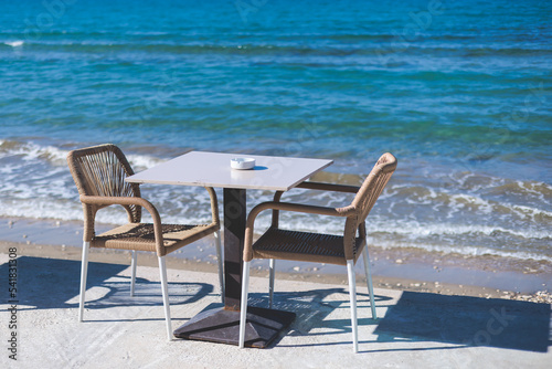 Restaurant terrace by the sea  seaside view cafe on the beach  empty chairs and tables Ionian sea shore  Greece  blue sea with crystal clear water