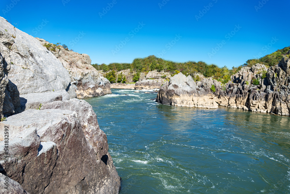 Mountain river flowing among the harsh sheer stones in the mountains. Sunny day, blue sky.
