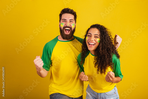 Fotobehang couple of brazil soccer supporters, dressed in the colors of the nation, black woman, caucasian man
