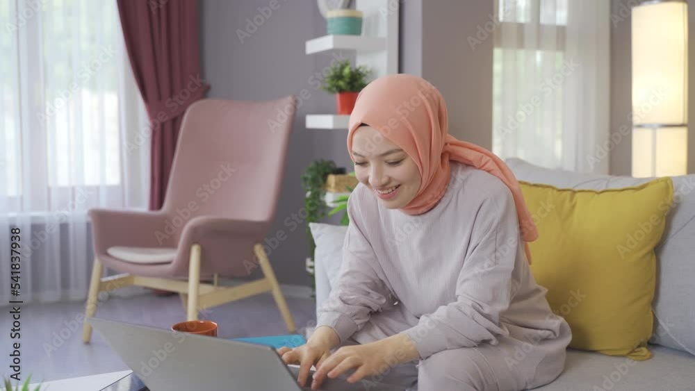 Muslim young woman looking at laptop and rejoicing.
Muslim woman in hijab looking at laptop surprised and happy.
