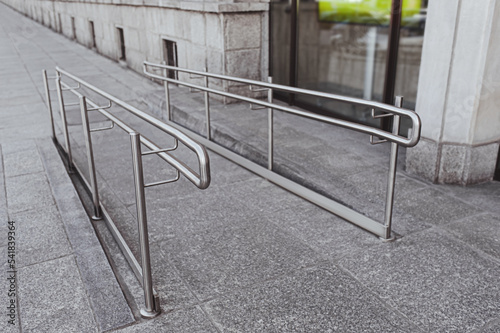 Tiled ramp with shiny metal railings outdoors