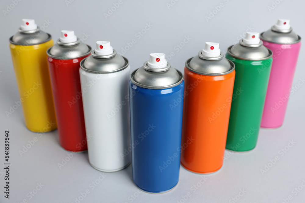 Colorful cans of spray paints on light grey background Colorful cans of spray paints on light grey background