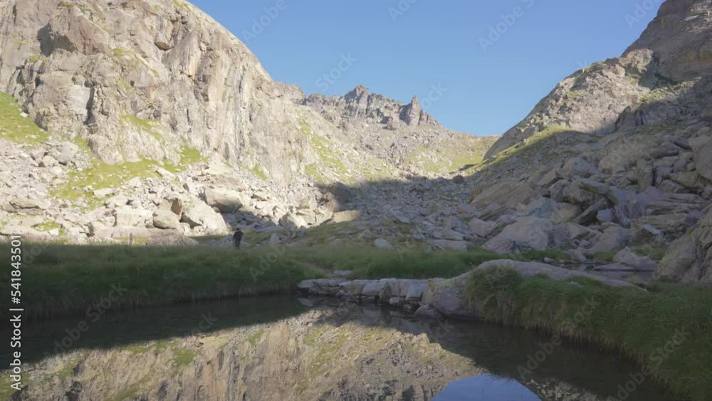 a man trekking in the mountains, pass a lake, the reflection in the water. a man trekking in the mountains, pass a lake, the reflection in the water.