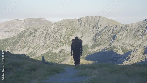 a man trekking alone in the mountains, walking towards the camera.