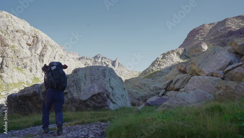 a man trekking alone between the rocks, walking away from the camera. photo