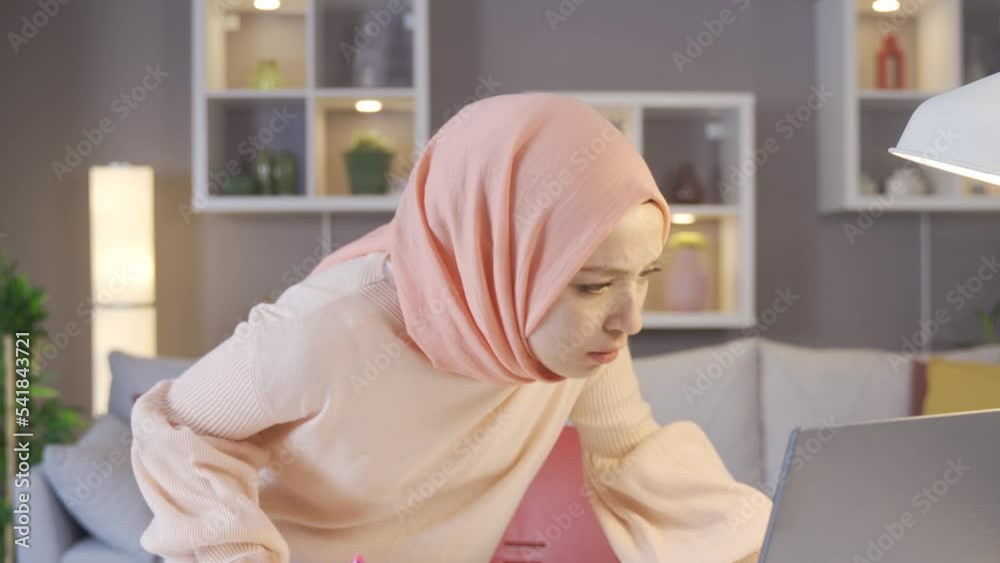 Young woman in hijab is sad.
Muslim young woman in hijab looking at laptop and upset at what she sees.
