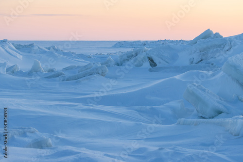 Winter arctic landscape. Ice hummocks on the frozen sea in the Arctic. View of snow and ice at sunset. Cold frosty winter weather. Harsh polar climate. Amazing nature in the far north in the Arctic.