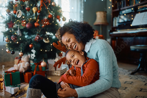 Cheerful African American mother and daughter have fun on Christmas day at home.
