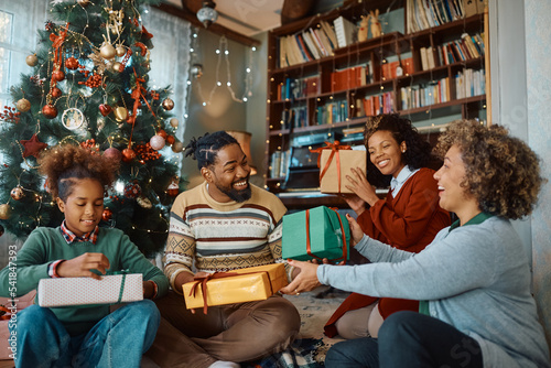 Happy black multigeneration family exchanging gifts at Christmas.