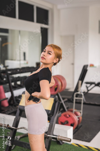 A lithe and svelte woman checking her figure while warming up at the gym.